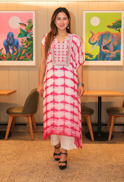 the Deli Dye Dream kaftan - a fusion of bohemian tie dye and elegant hand embroidery. Made with pure georgette fabric, this one-sided kaftan is perfect for breezy summer days. Its box styles add a touch of sophistication as you walk in style and make a statement. The dress comes with one inner and white straight fit cotton pants.