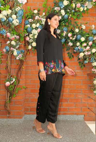 the Empress Ebony coord set from Destiny by Anjali. This designer western wear features a sleek black tone, crafted from luxurious bombarg satin fabric. The shirt is beautifully adorned with intricate zardozi hand embroidery at the bottom, giving it an elegant, floral touch. Perfect for all-weather and occasion wear, this trending coord set blends timeless tradition with contemporary style, making it a must-have for any wardrobe. Elevate your look with this chic and versatile set for any occasion.