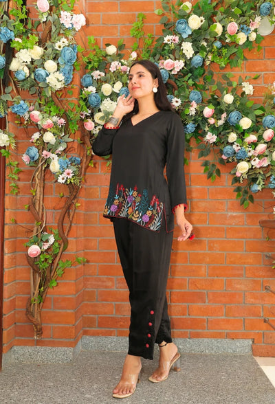 the Empress Ebony coord set from Destiny by Anjali. This designer western wear features a sleek black tone, crafted from luxurious bombarg satin fabric. The shirt is beautifully adorned with intricate zardozi hand embroidery at the bottom, giving it an elegant, floral touch. Perfect for all-weather and occasion wear, this trending coord set blends timeless tradition with contemporary style, making it a must-have for any wardrobe. Elevate your look with this chic and versatile set for any occasion.