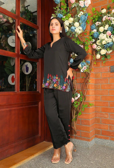 the Empress Ebony coord set from Destiny by Anjali. This designer western wear features a sleek black tone, crafted from luxurious bombarg satin fabric. The shirt is beautifully adorned with intricate zardozi hand embroidery at the bottom, giving it an elegant, floral touch. Perfect for all-weather and occasion wear, this trending coord set blends timeless tradition with contemporary style, making it a must-have for any wardrobe. Elevate your look with this chic and versatile set for any occasion.