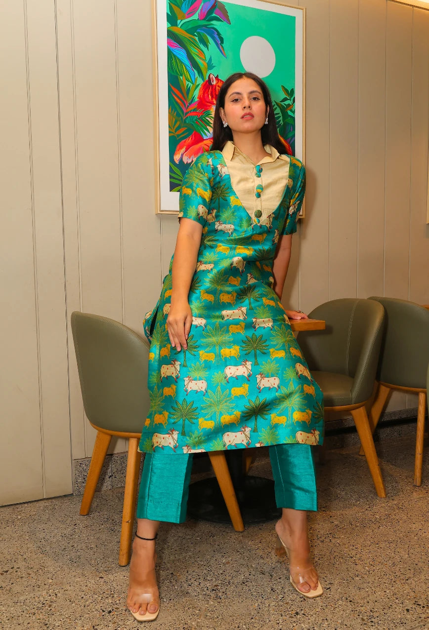 the Kriti Kavya tunic kurti set from Destiny by Anjali. This designer tunic set, crafted from lustrous mango silk fabric in a vibrant green shade, features delicate prints of cows, trees, and bushes inspired by the Madhuvan theme. The shining silk fabric makes it a trending choice for every season, offering comfort and style for all-weather wear. Ideal for festive events or casual outings, this occasion wear kurti set is perfect for all occasions, combining traditional charm with modern flair. Elevate your 